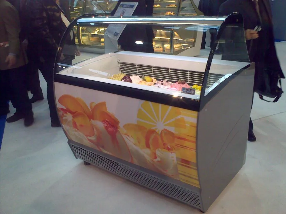 Eine Frau steht neben einer Vitrine voller Kuchen.