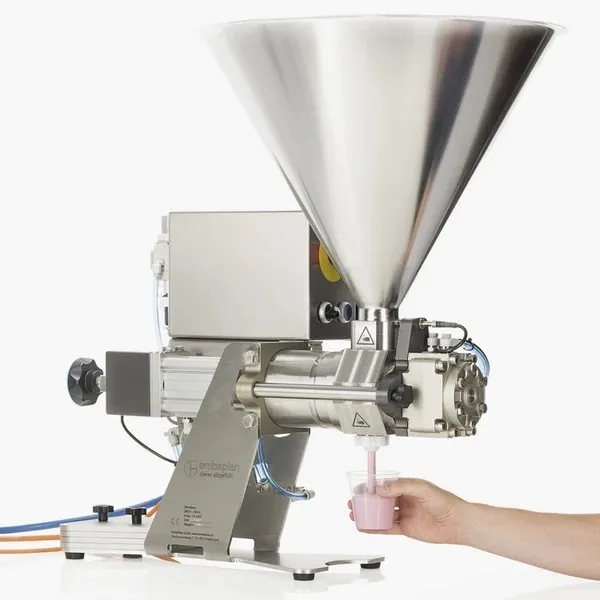 Eine Person, die eine Tasse vor eine Maschine hält.
